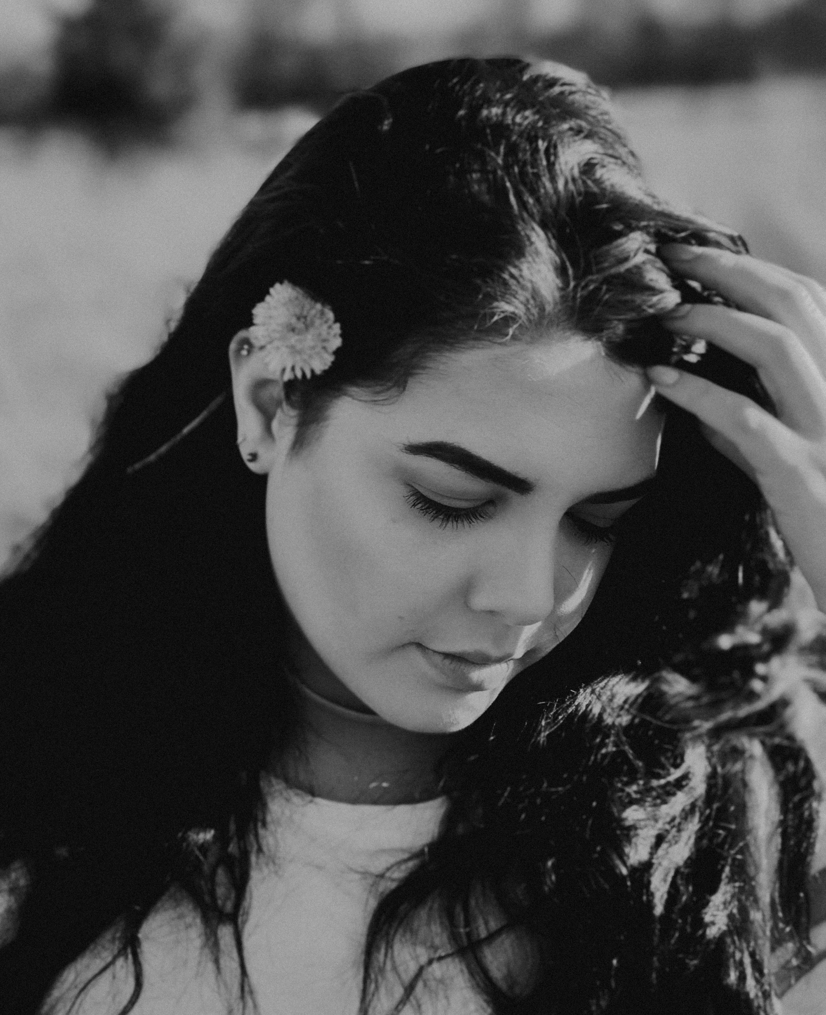 grayscale photo of woman closing her eyes while holding hair